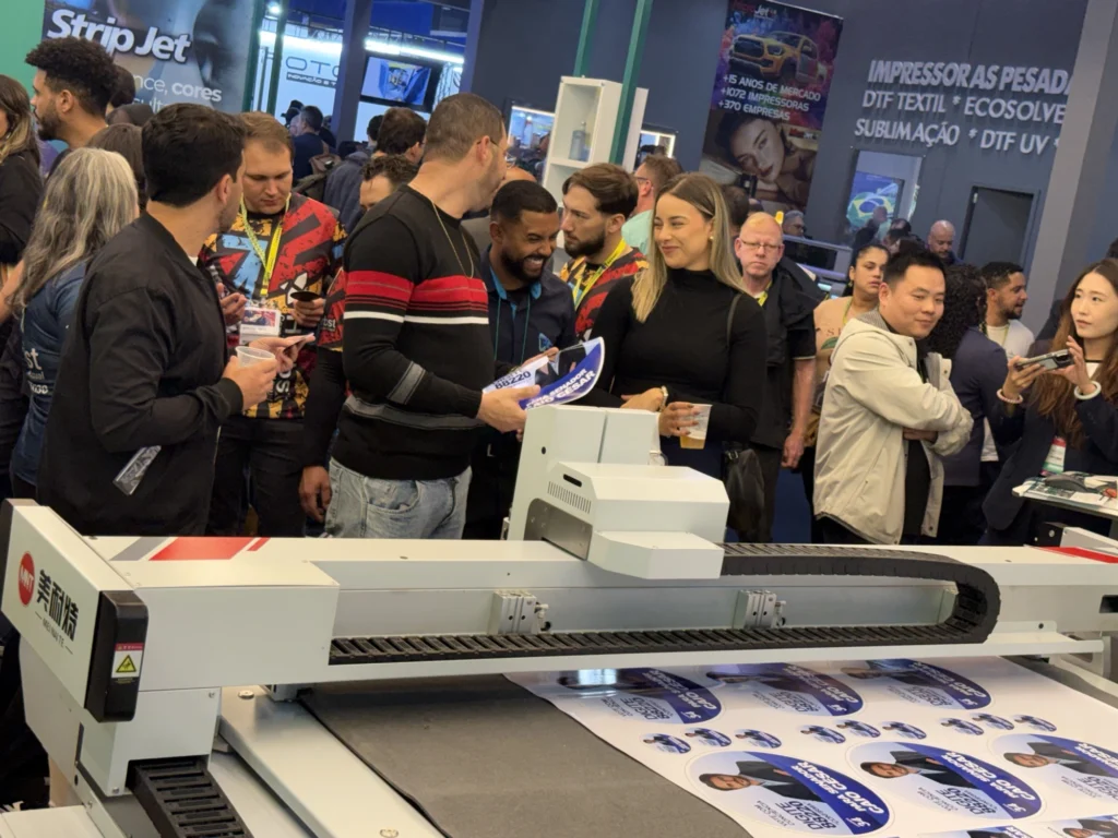 MEINAITE CR 2516T digital cutting table cutting a full sheet of printed labels during a live demo at Future Print 2026 in São Paulo, Brazil.