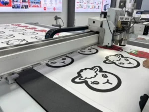 MEINAITE CR 2516T digital cutting table processing a full sheet of printed label stickers at the MNT booth during Future Print 2026 in Brazil.