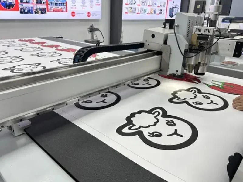 MEINAITE CR 2516T digital cutting table processing a full sheet of printed label stickers at the MNT booth during Future Print 2026 in Brazil.