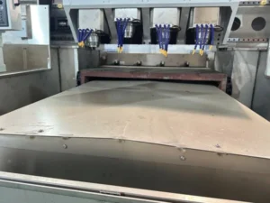 Side-by-side comparison of a three-axis CNC router and a five-axis CNC router in a machine shop