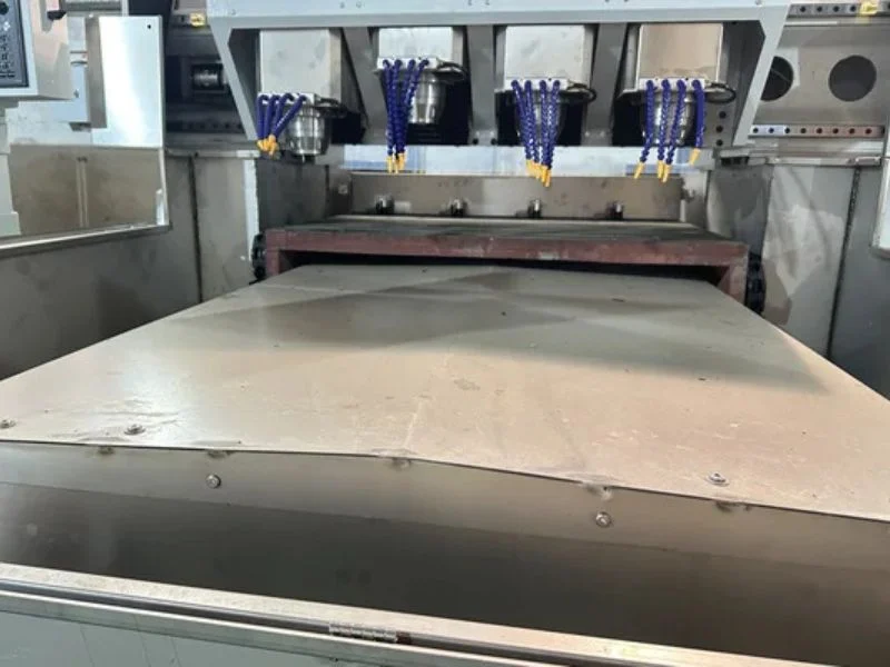 Side-by-side comparison of a three-axis CNC router and a five-axis CNC router in a machine shop