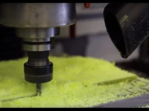 Router spindle machining yellow-green G10 laminate with dust extraction at the cutter head
