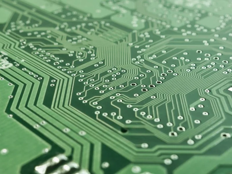 Copper-clad FR-4 panel being depaneled with fiducial marks visible on the board