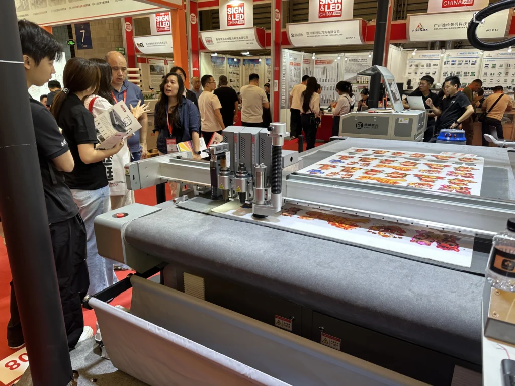 MNT MEINAITE C2516T digital cutter with CCD camera and milling spindle contour-cutting printed graphics on a belt conveyor at SIGN CHINA 2026